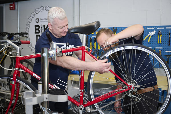 Cyclists repairing a bike at the Penn State Bike Den