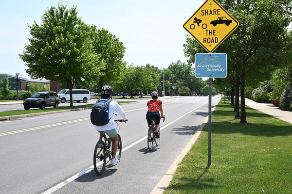 Cyclists biking near the Bicycle Friendly University Sign