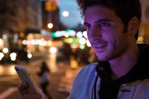 Student downtown looking at a phone in the dark