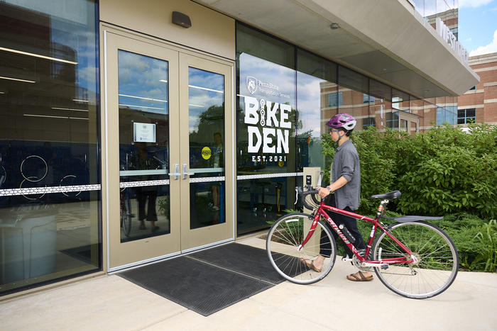 Cyclist pushing bike to the Bike Den entrance